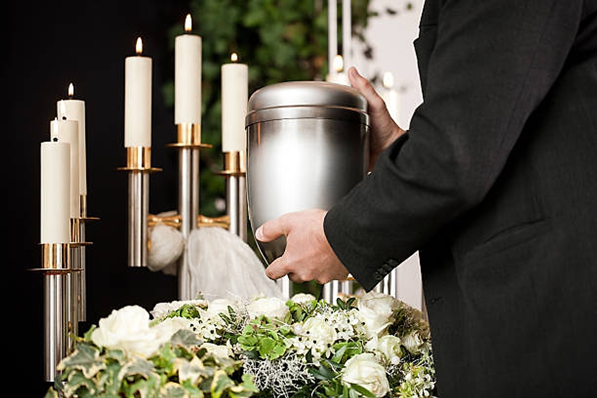 Urna cineraria fra i ceri accesi e le composizioni di fiori bianchi